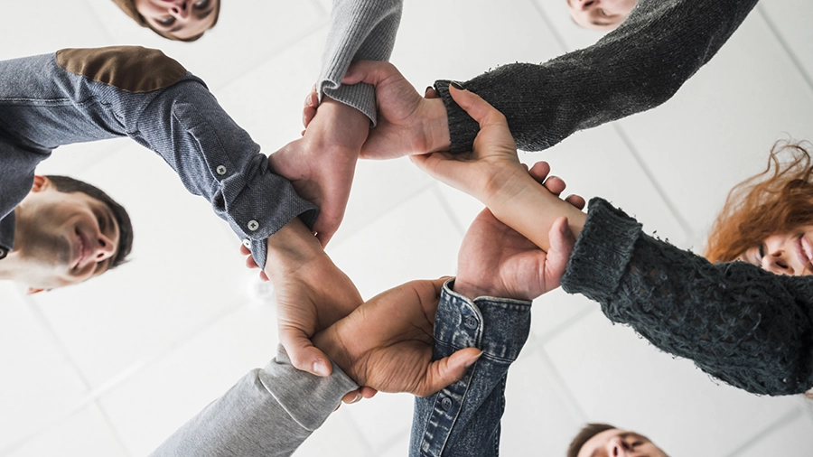 Equipe de seis pessoas onde elas estão segurando no pulso, uma das outros formando um circulo ou uma corrente